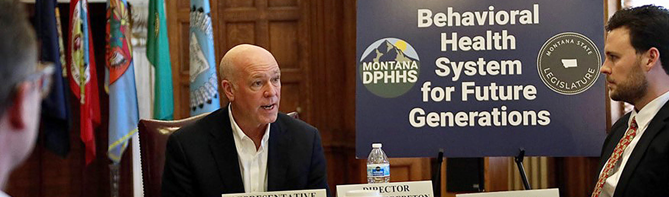 Greg Gianforte talking with Charlie Brereton in front of poster