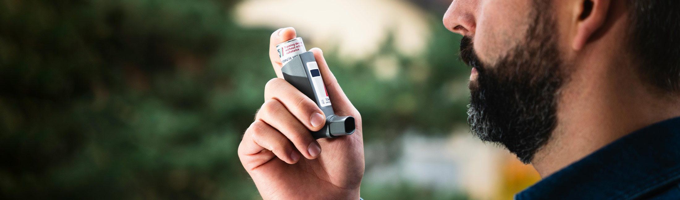 Man with beard holding asthma inhaler