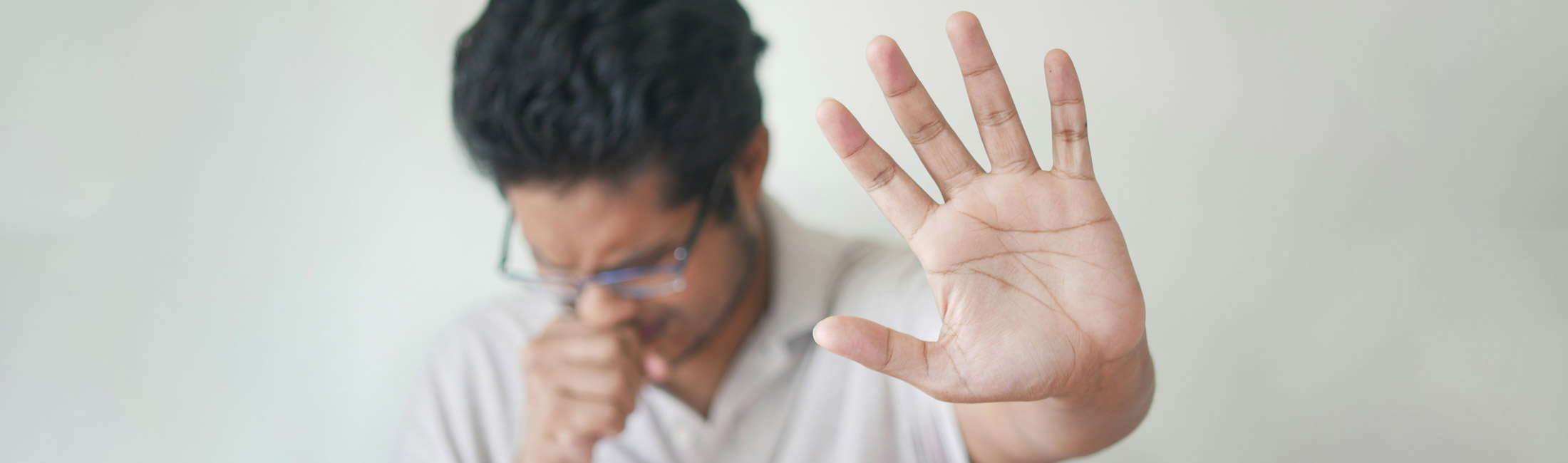 man coughing with hand up in front of body