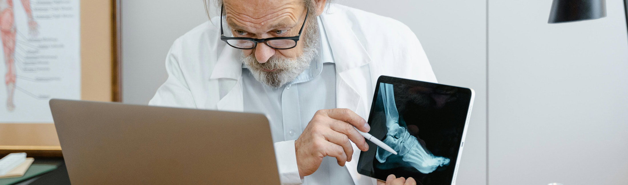 medical professional man pointing to xray of foot shown on tablet