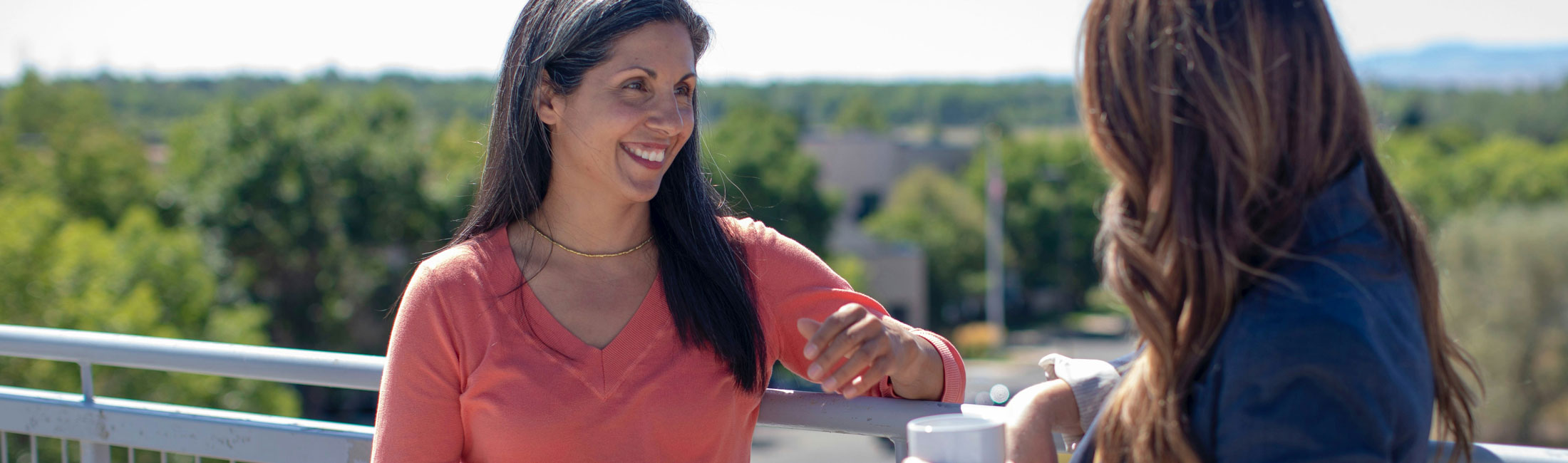 two women standing outdoors on balcony 