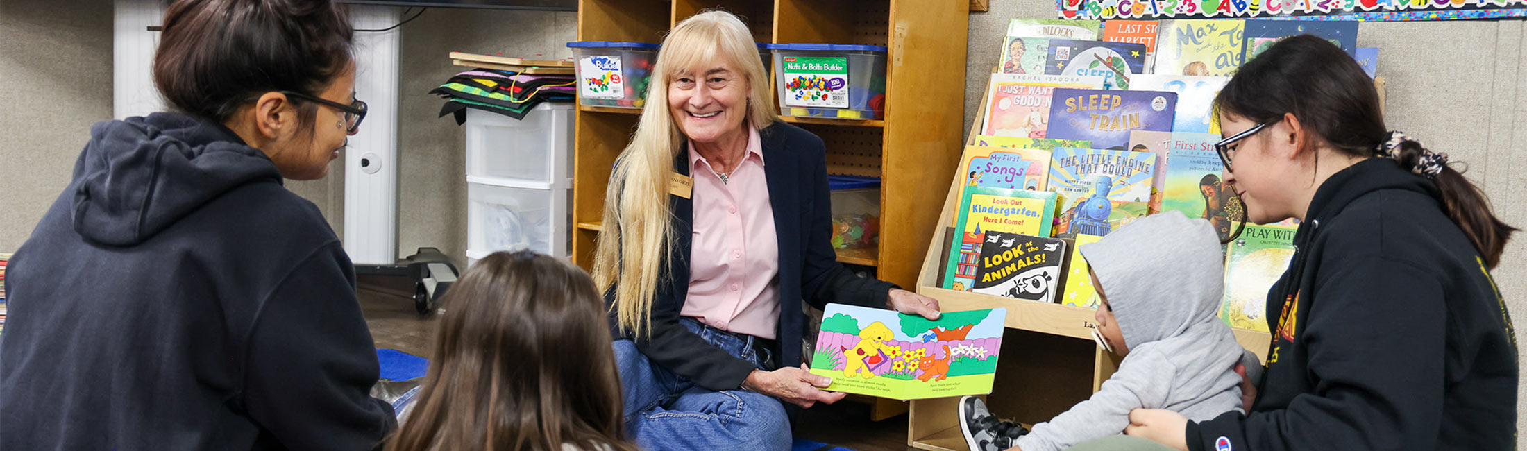Susan Gianforte on floor reading to children