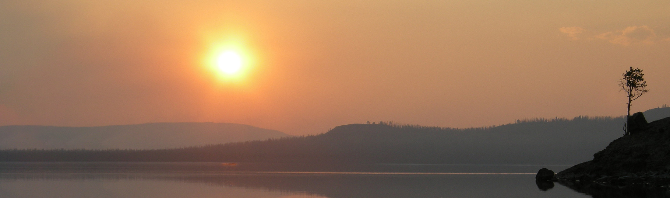 sun over lake with smoky sky