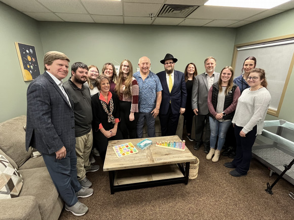 DPHHS staff and Rabbi Chaim Bruk pose for a photo inside the newly remodeled Bozeman CFSD family visitation room on Monday, Dec. 23.