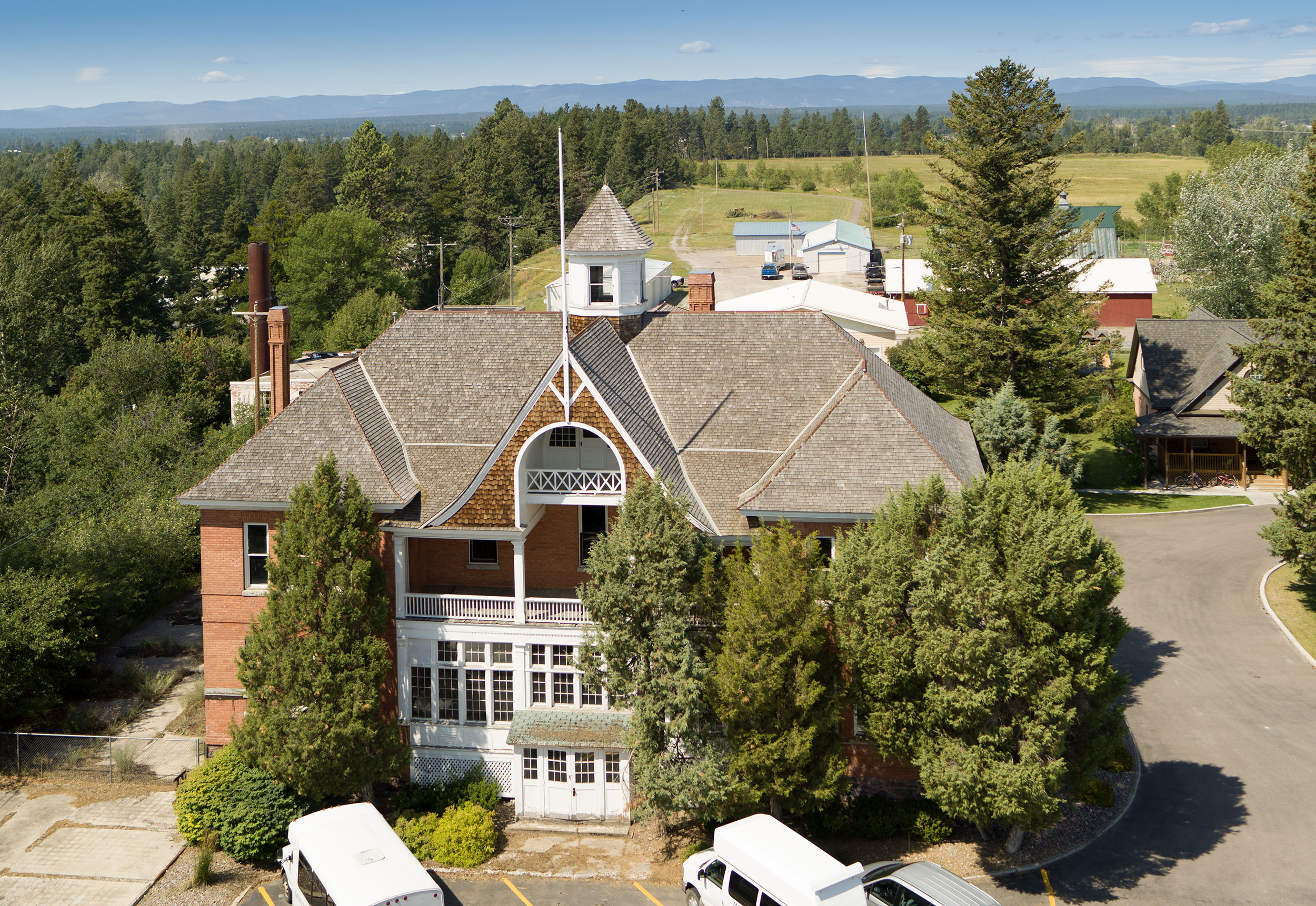An aerial view of the main building of the Veterans Home. It is light brown brick with a slanted roof. There is a porch visible at the back of the home.