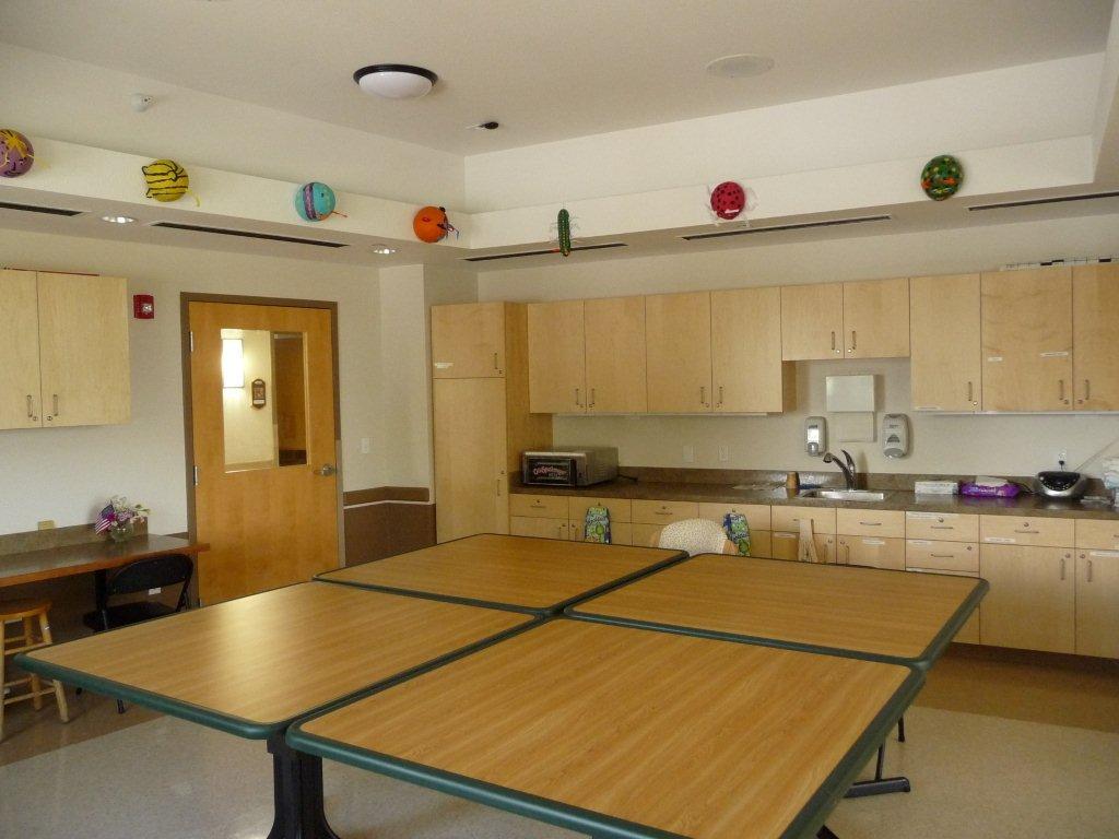 A picture of the west activity room inside the Veterans home. There are four small tables put together in a room, and a sink.